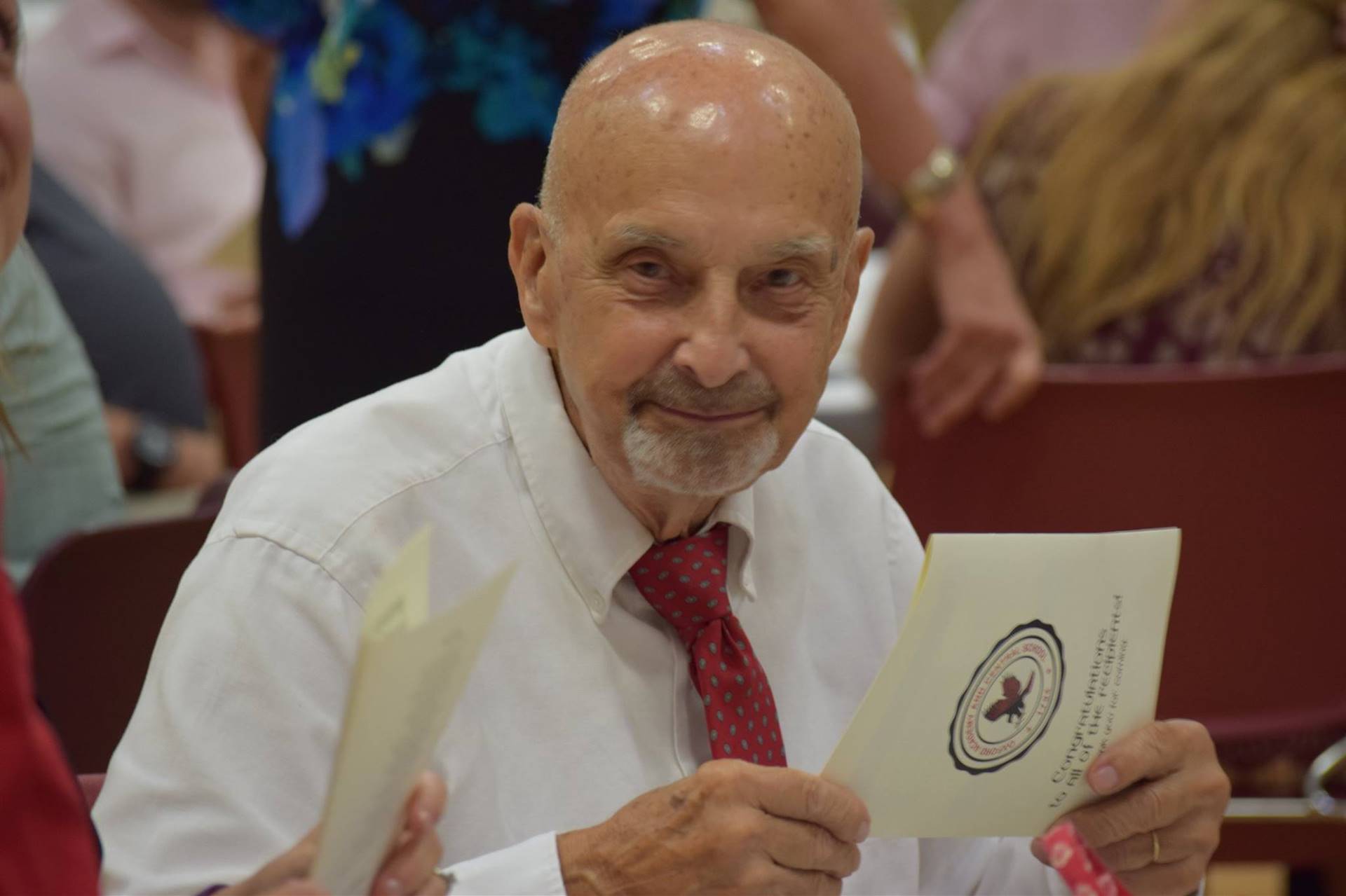 A man holding the ceremony program during dinner.