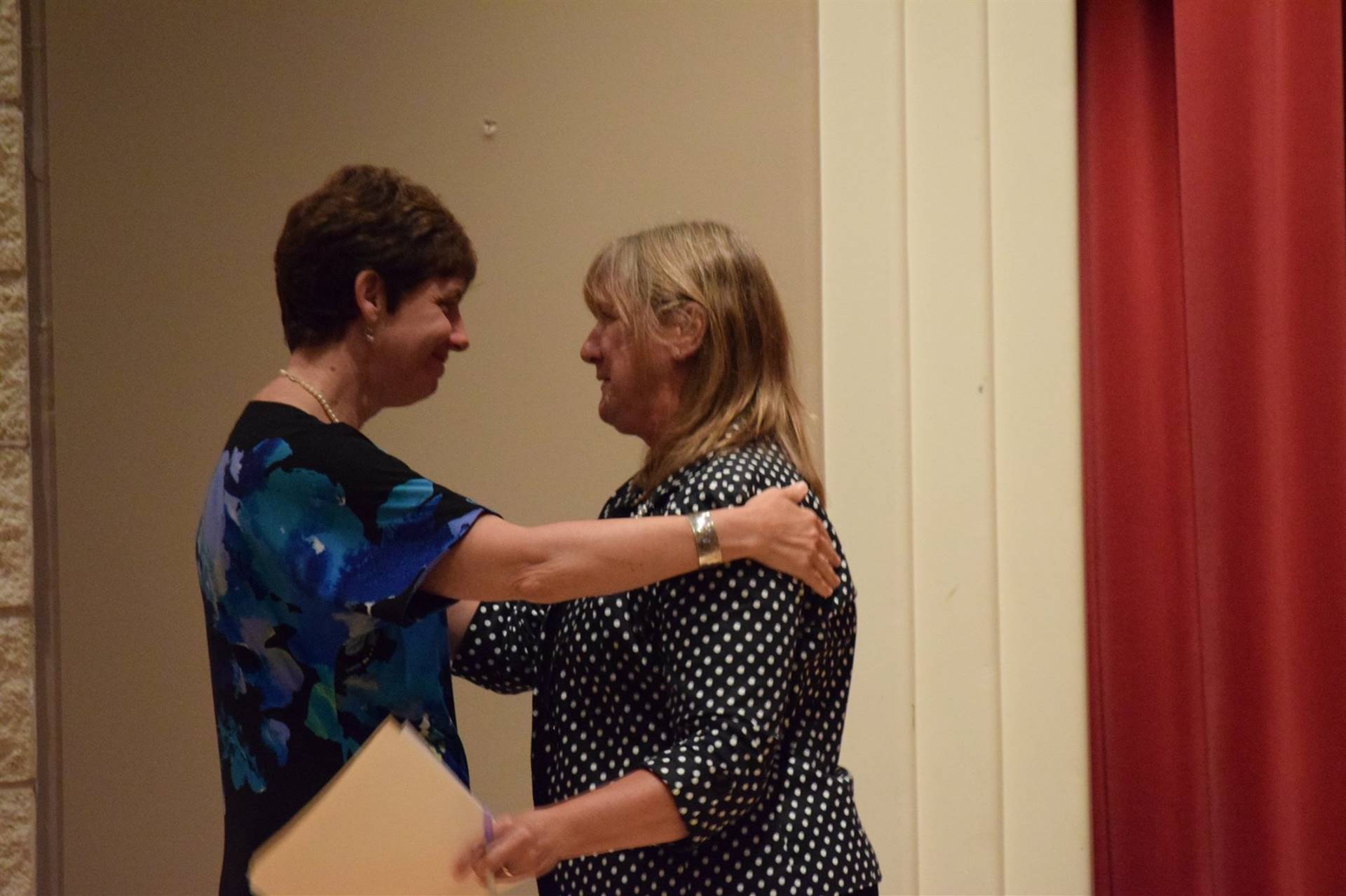 Honoree Dr. Nelson receiving a hug from a lady in attendance.