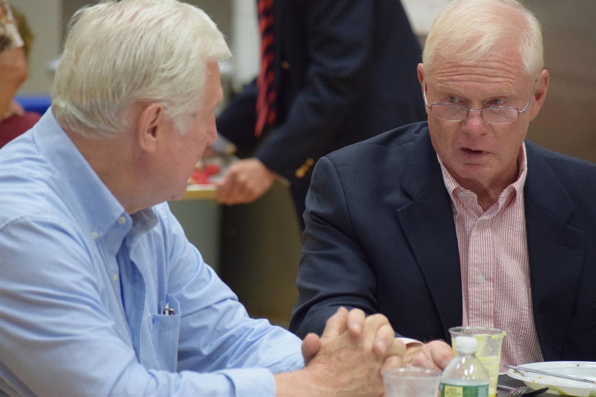 Two men talking while eating dinner.