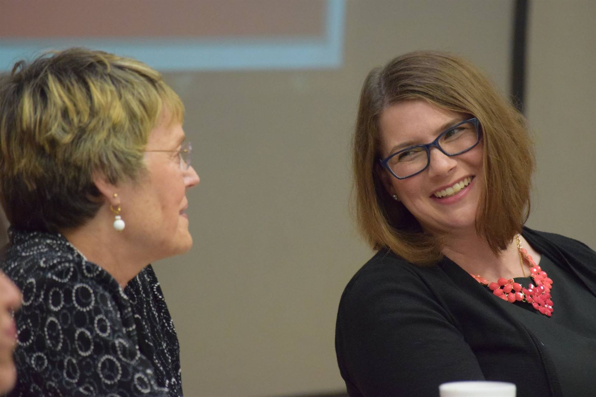 Two women laughing sitting at dinner.