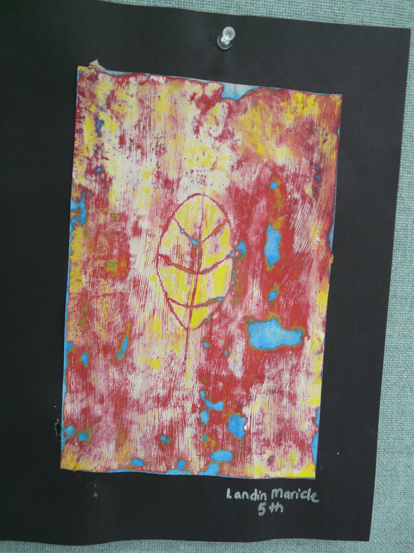 outline of a small leaf on smeared red, blue and yellow paper