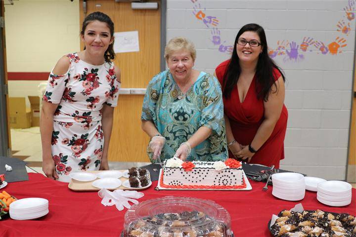 picture of three ladies cutting and serving cake