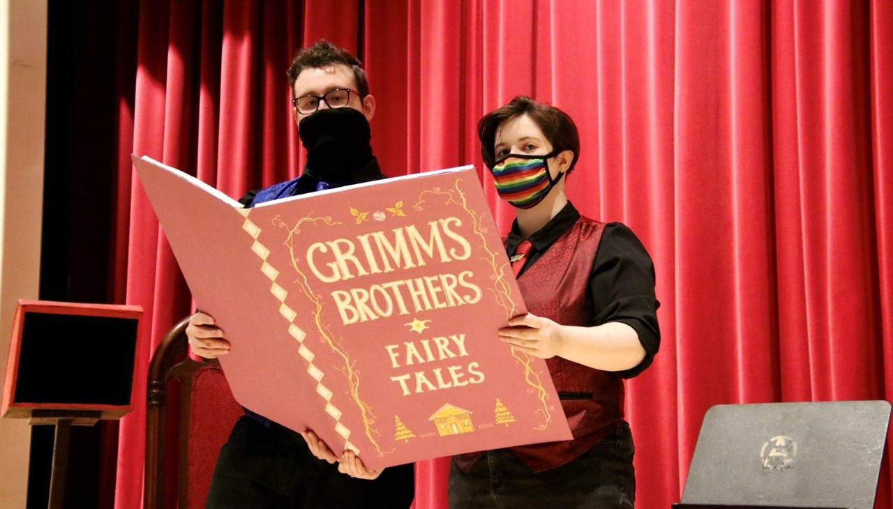 Play - male and female actor reading a large book &#34;Grimms Brothers&#34;