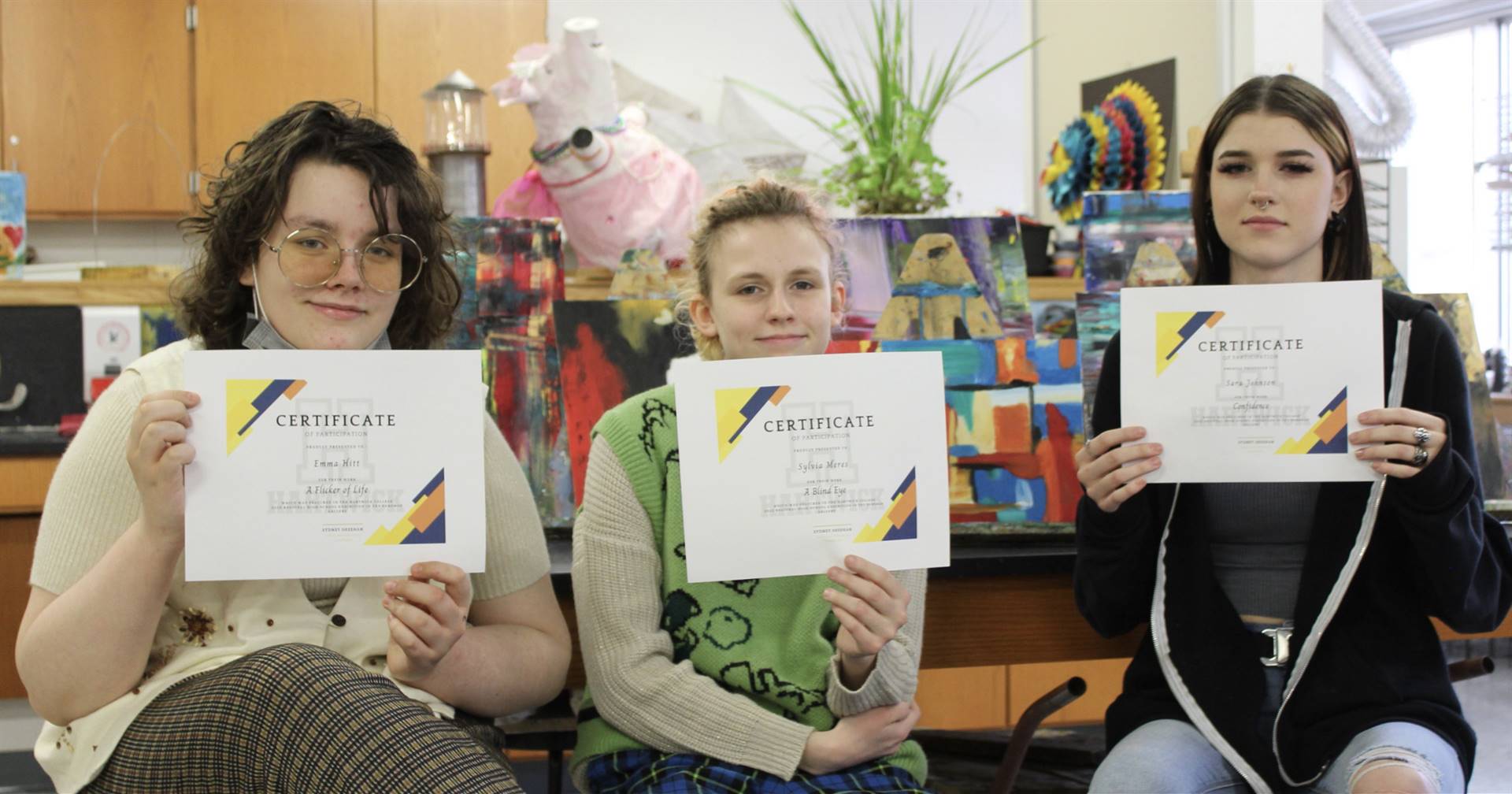 HS female art students holding art award certificates