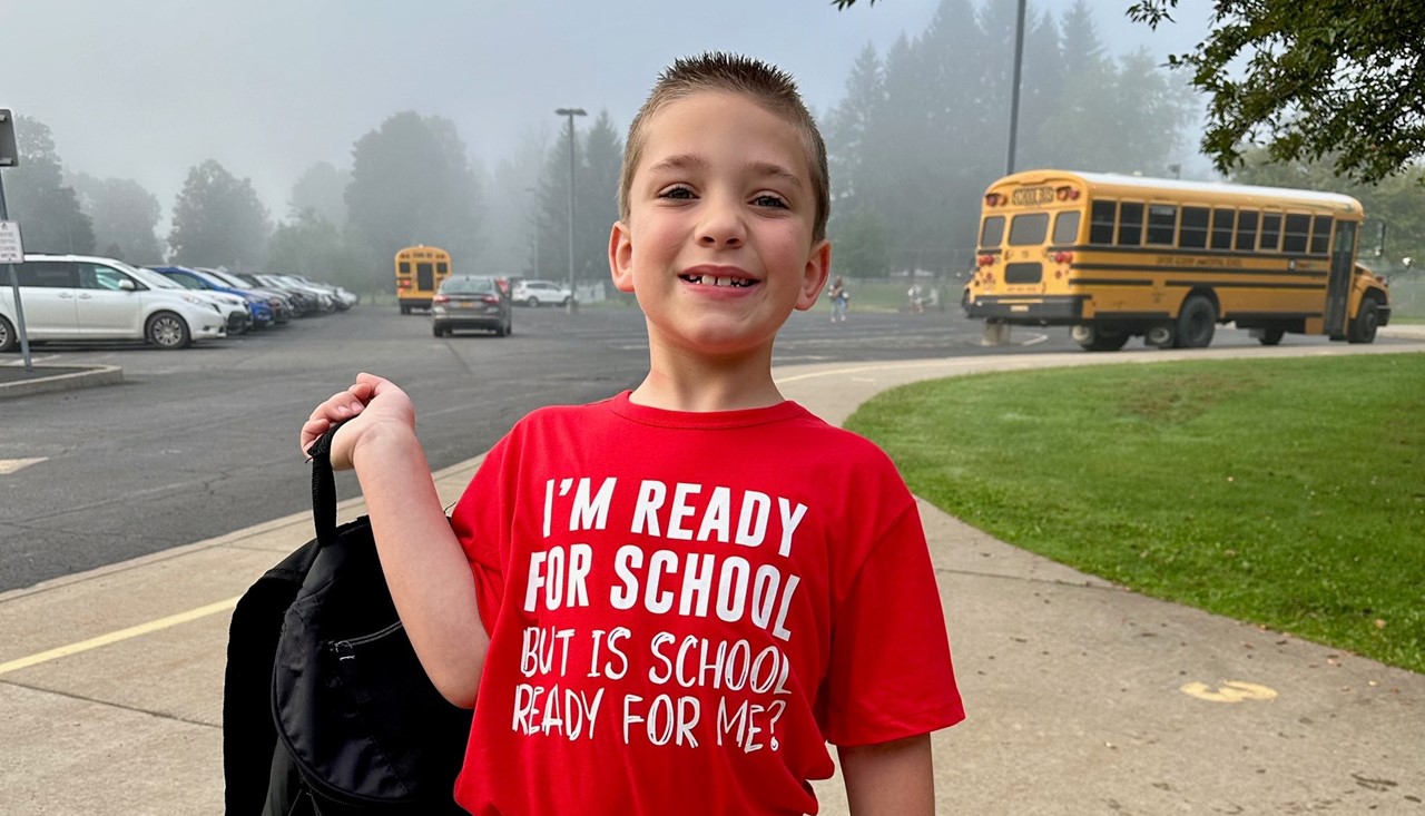 Primary school student posing with backpack in hand