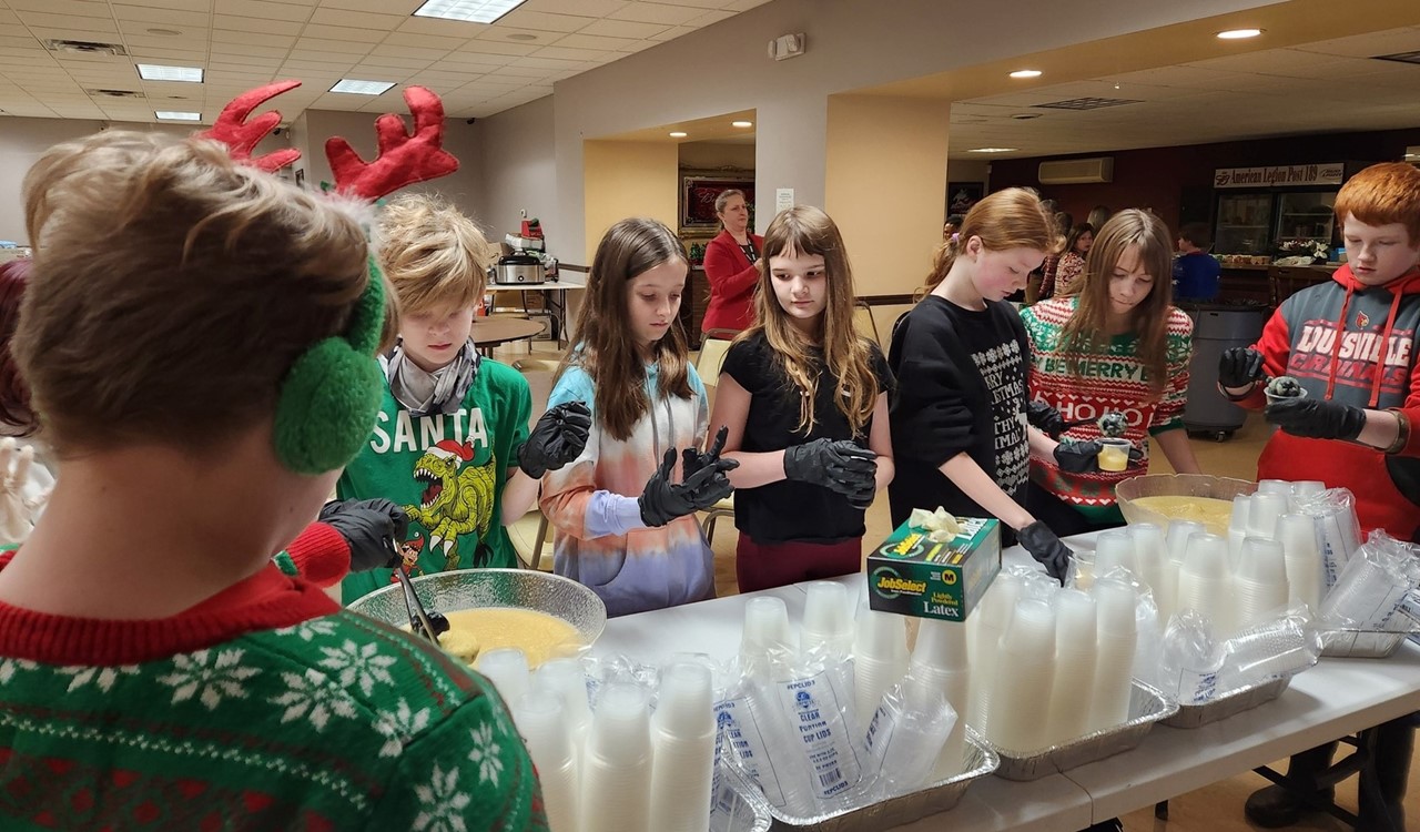 Students filling apple sauce for Christmas free meals